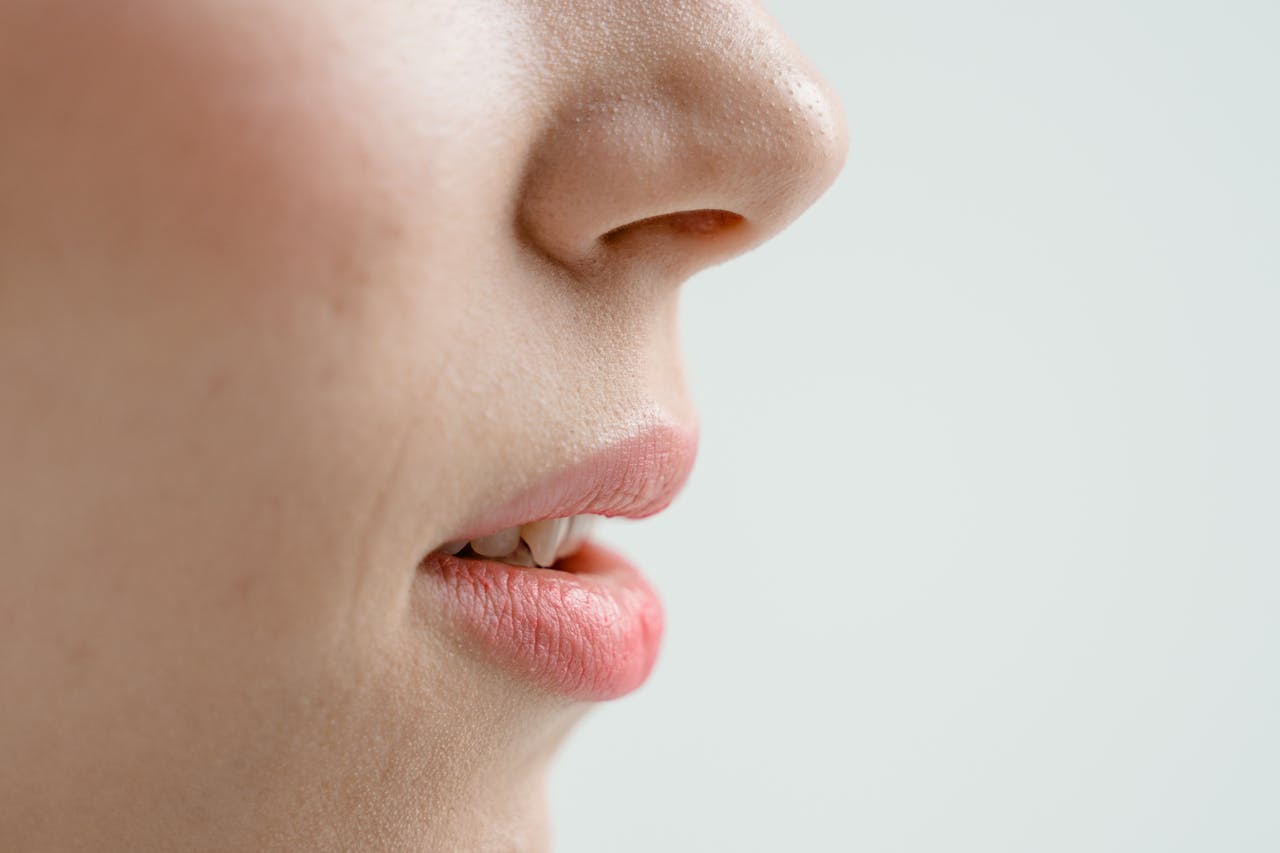 Detailed side view of a woman's nose and lips with natural skin texture. Perfect for beauty and skincare content.